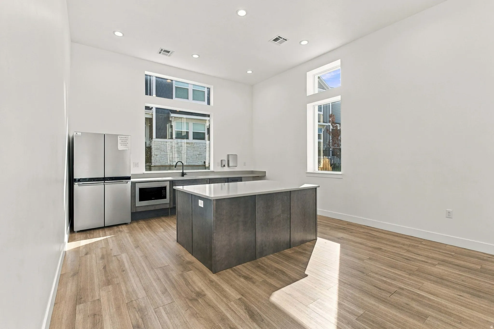 Contemporary kitchen featuring a center island, stainless steel appliances, recessed lighting, wood-finish flooring, and expansive windows