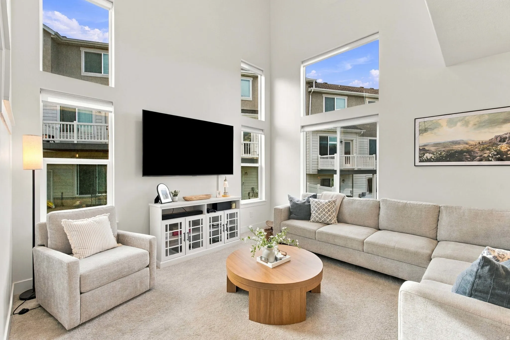 Living room featuring high ceilings, multiple large windows, and wall-mounted television