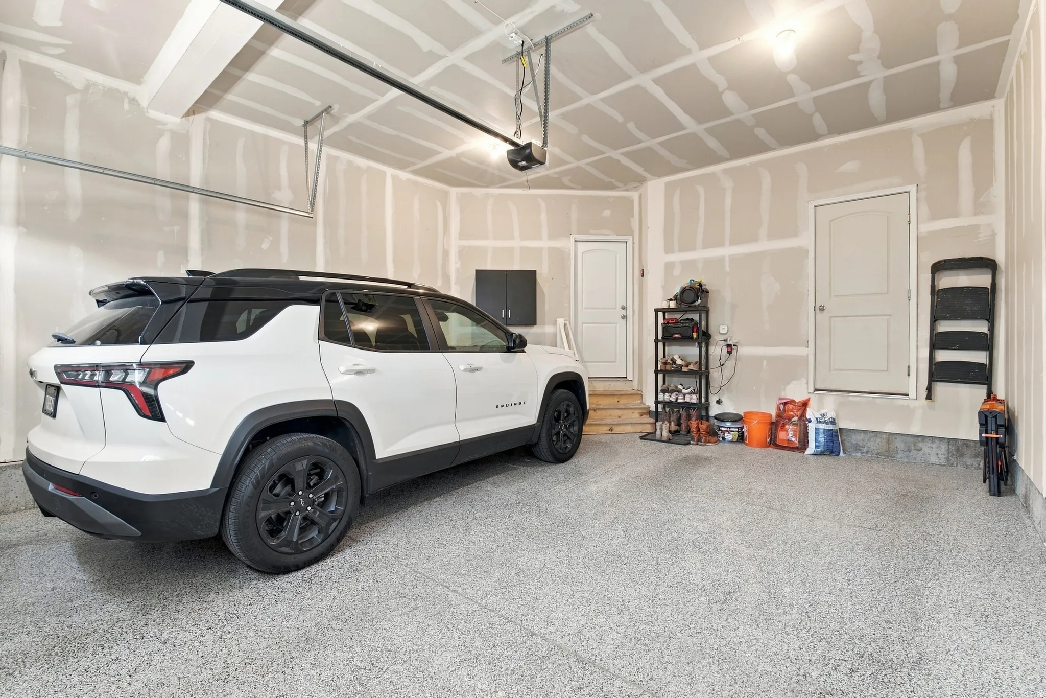 Garage featuring a speckled epoxy floor, dual access doors, and overhead lighting
