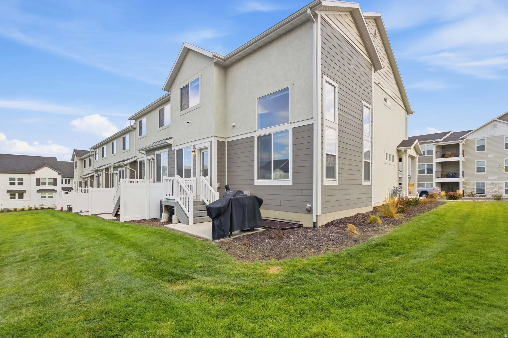 Expansive green space with an exterior featuring siding and stucco finishes