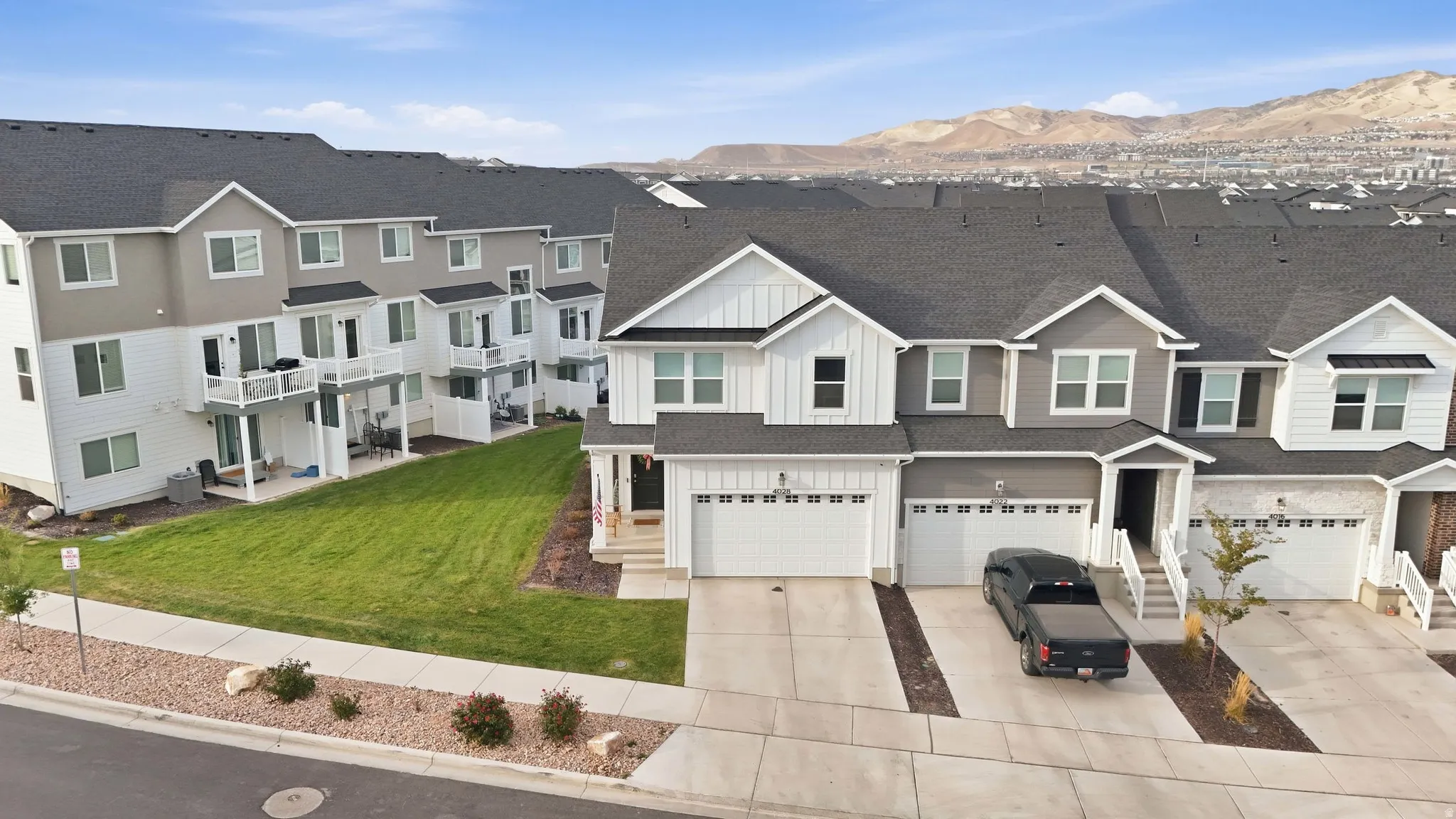 Modern townhome exterior with dark gray siding, white trim, and a dark shingle roof