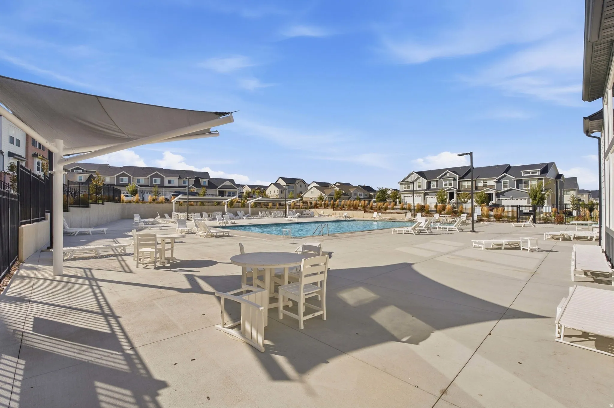 Expansive pool deck with a rectangular swimming pool, multiple lounge chairs, and shaded outdoor seating areas