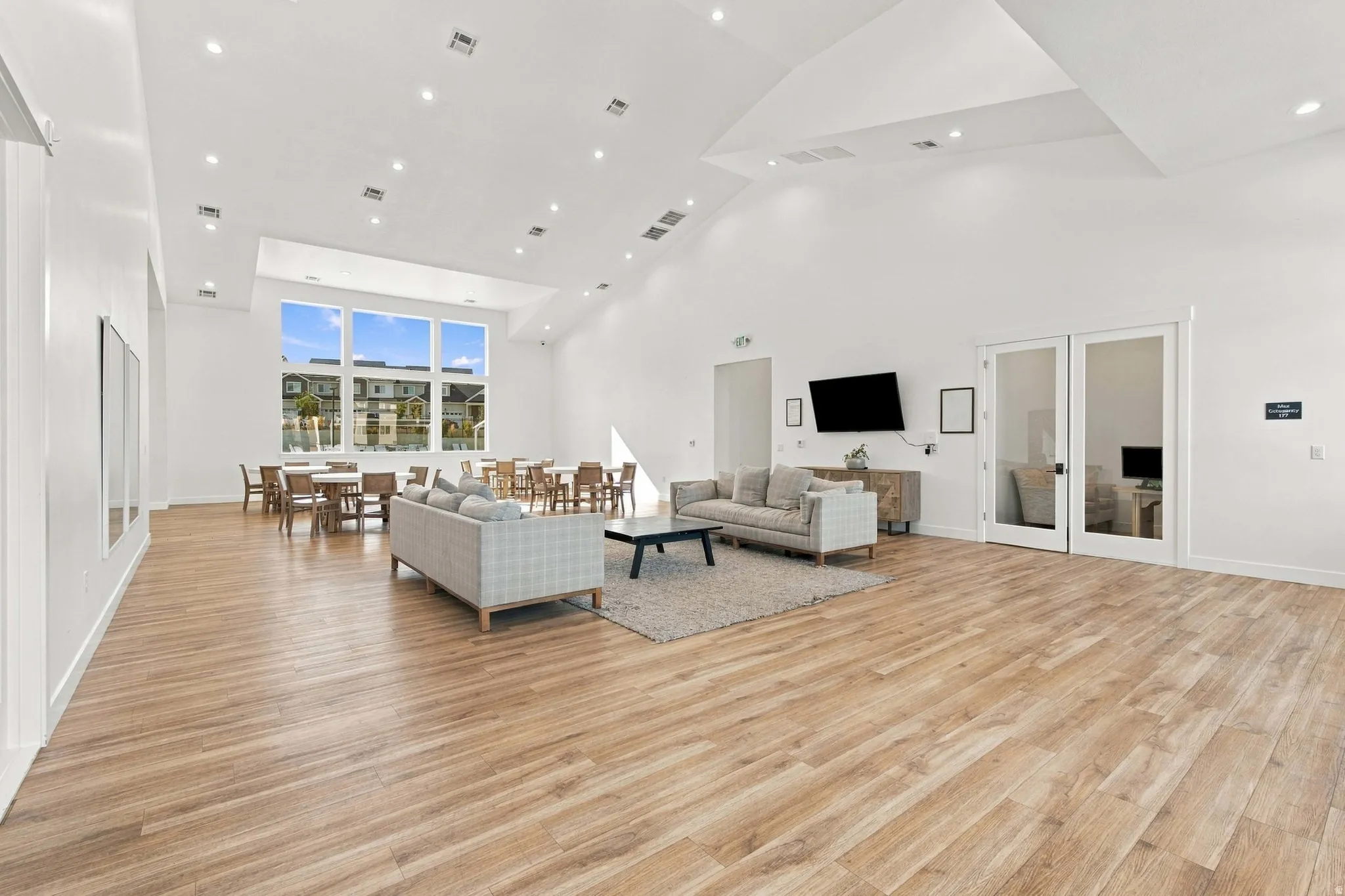 Spacious common area featuring vaulted ceilings, wood-finish flooring, recessed lighting, and large windows