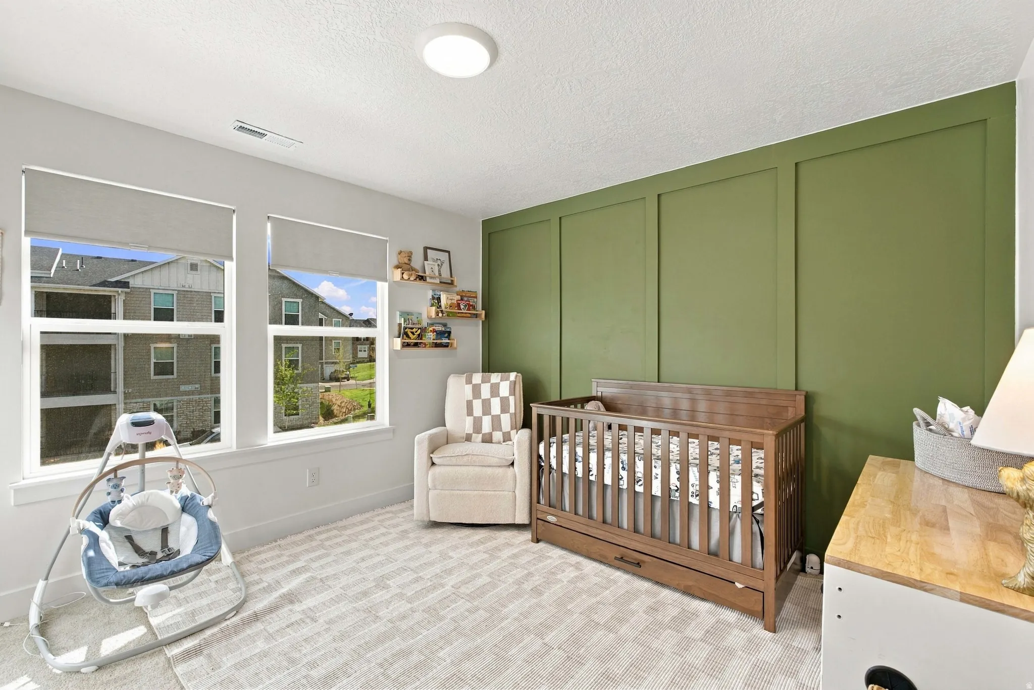 Recessed ceiling light, dual pane windows with roller shades, accent wall with panel molding, and light-colored wall-to-wall carpeting