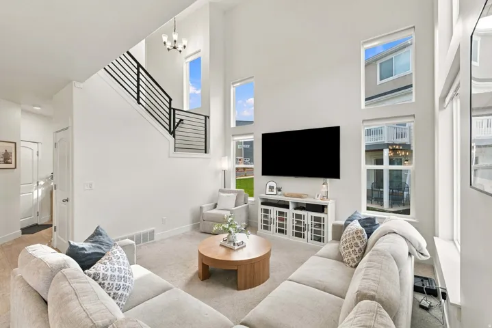 Two-story living area featuring a modern staircase with horizontal metal railings, multiple transom windows, and a built-in media console