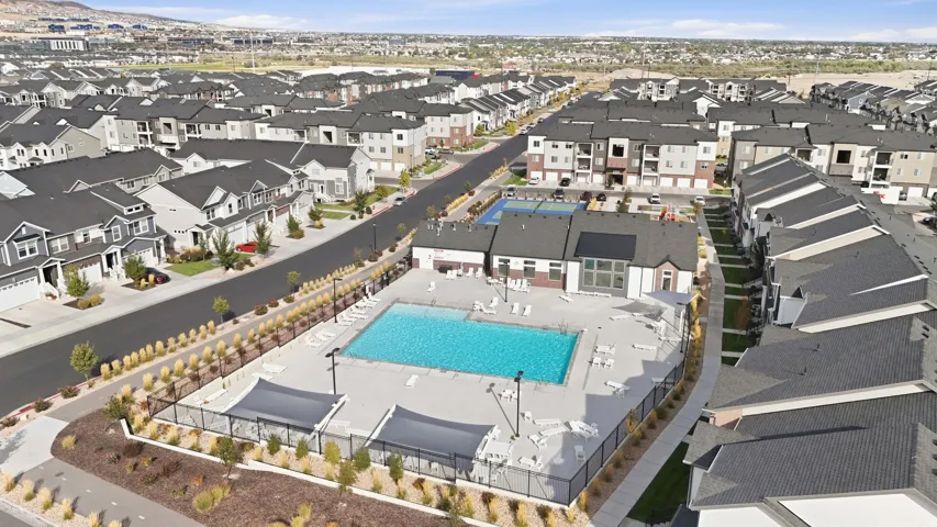 Community swimming pool with surrounding lounge chairs and shaded cabanas, hardscaped pool deck, and adjacent clubhouse building