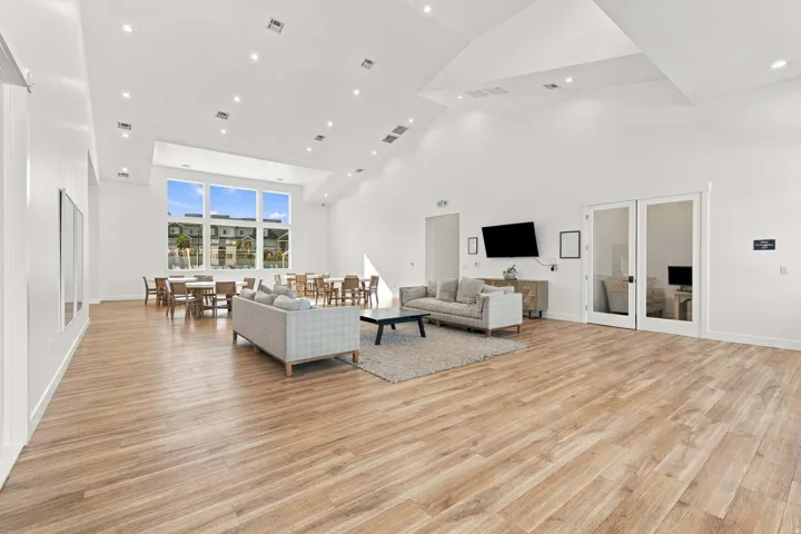 Spacious common area featuring vaulted ceilings, wood-finish flooring, recessed lighting, and large windows