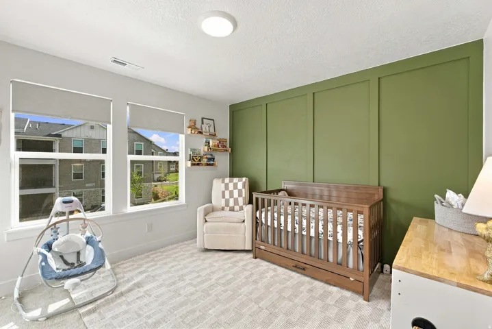 Recessed ceiling light, dual pane windows with roller shades, accent wall with panel molding, and light-colored wall-to-wall carpeting