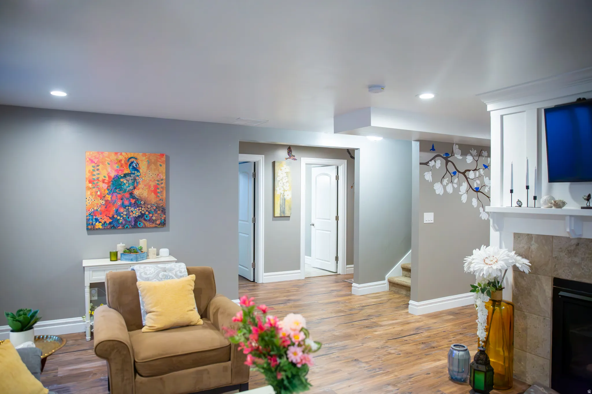 Recessed lighting, wood-finish flooring, neutral wall tones, white trim, and a built-in fireplace with a tile surround and white mantel