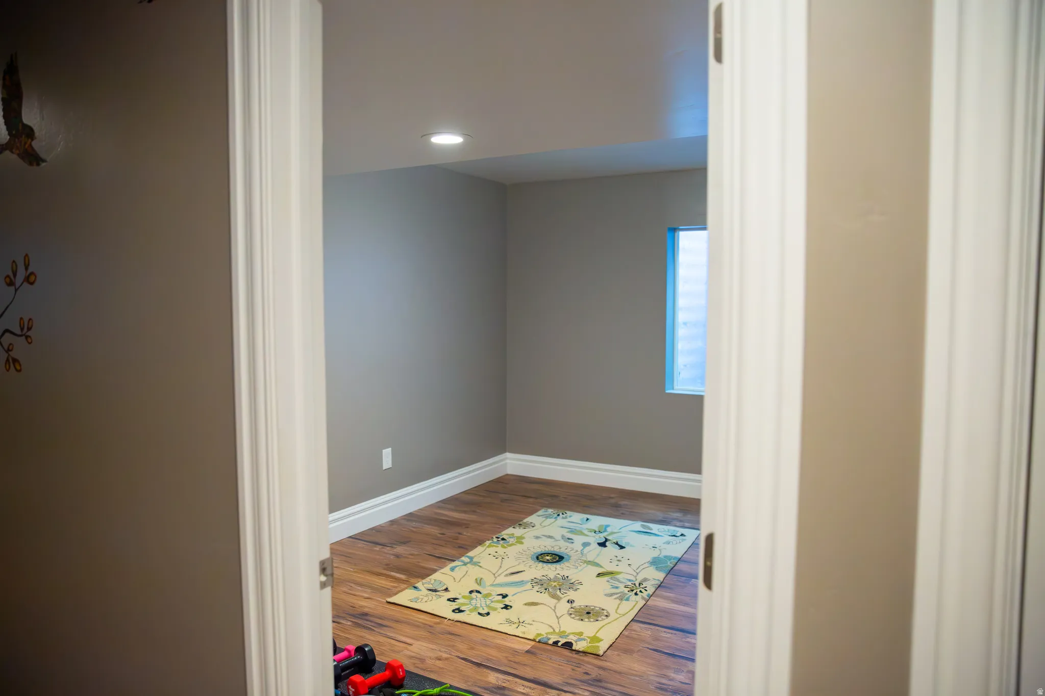Recessed lighting, wood-finish flooring, and a window with white trim