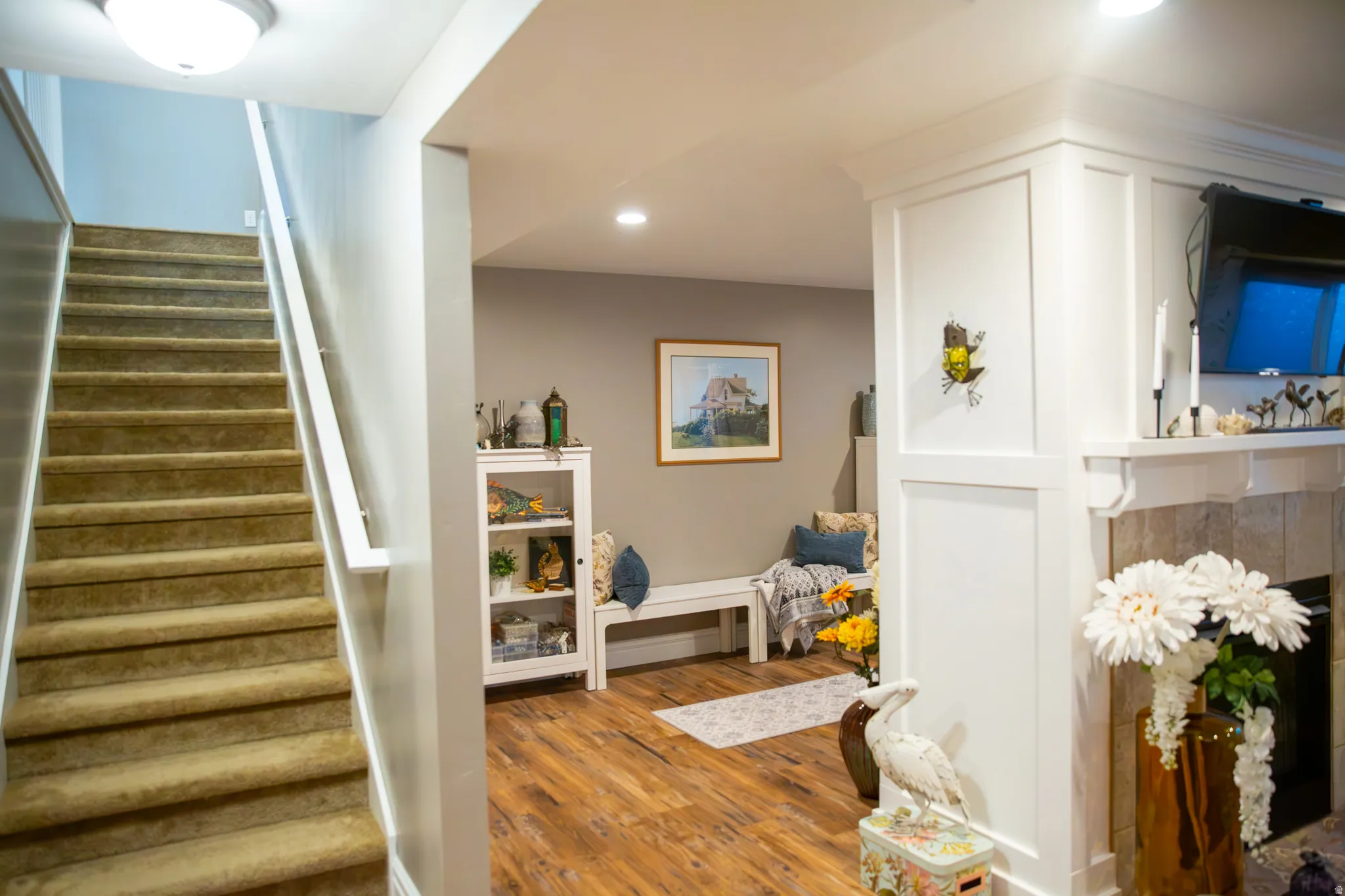 Carpeted staircase with white handrail, recessed lighting, and wood-finish flooring