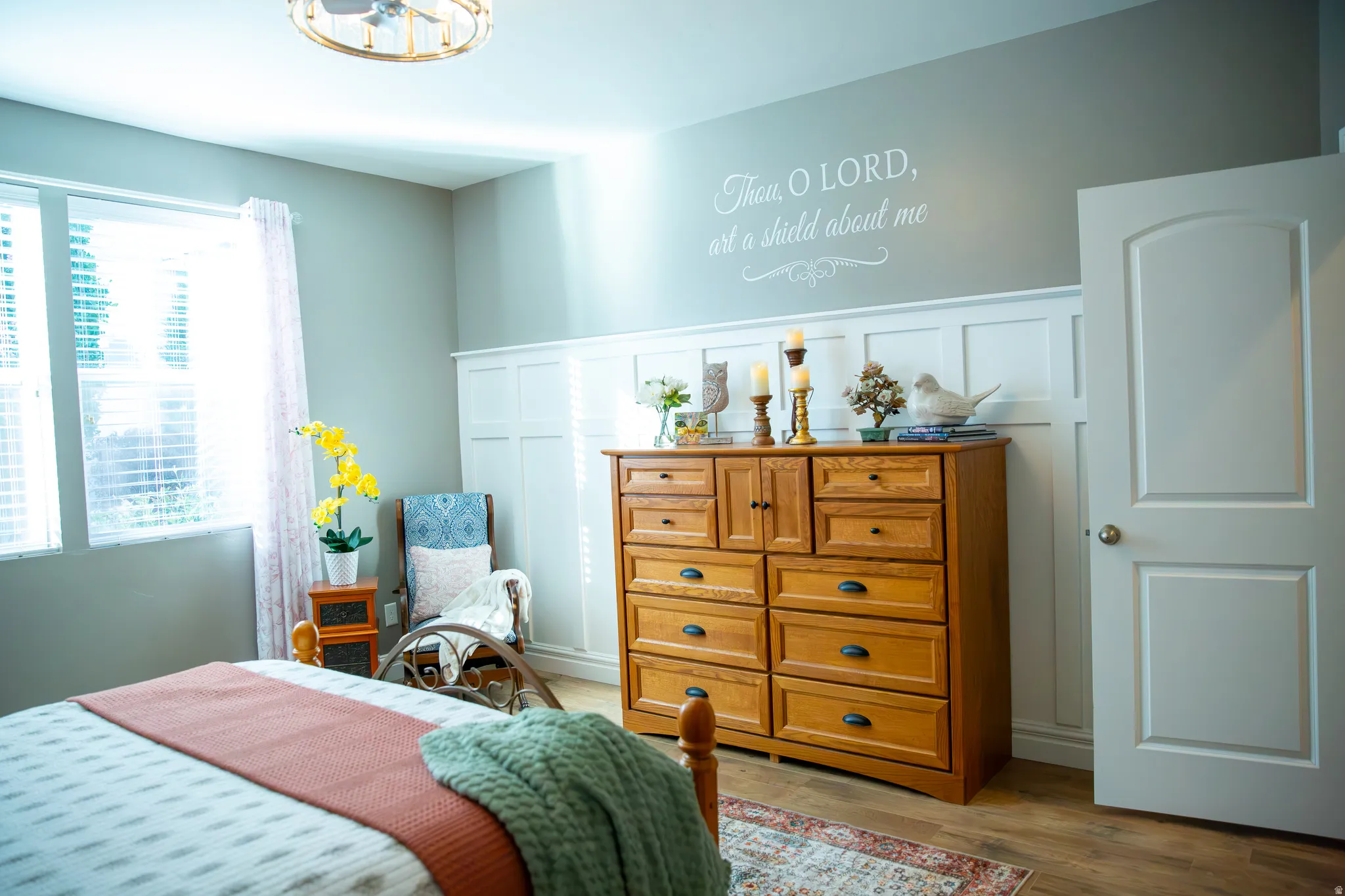 Wood-finish flooring, white paneling, and an arched two-panel interior door
