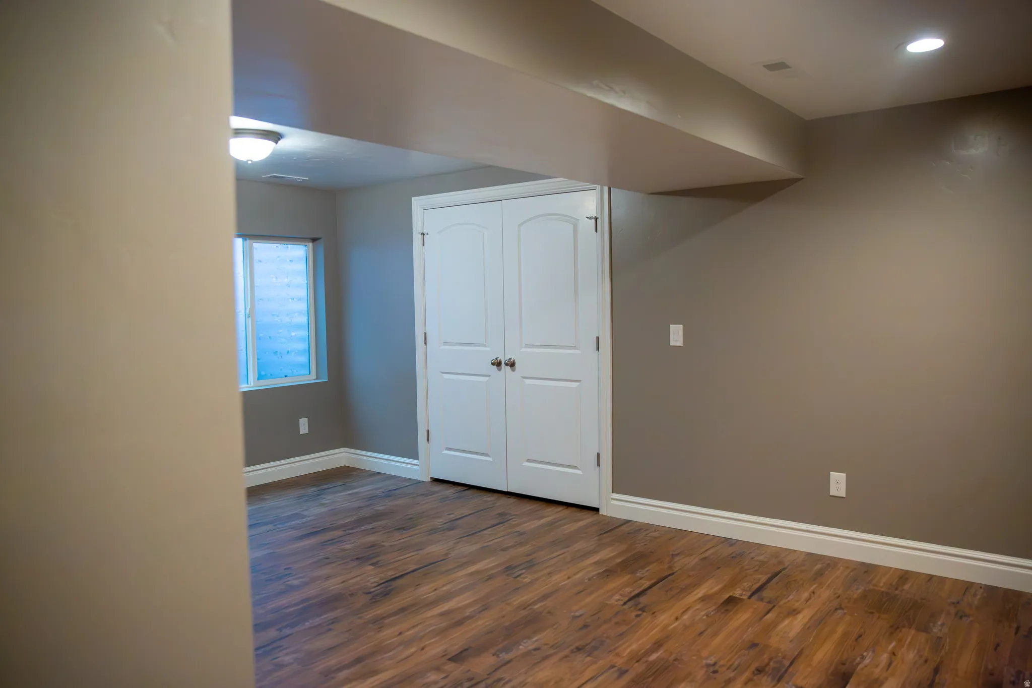 Wood-finish flooring, neutral wall tones, white trim, and a window