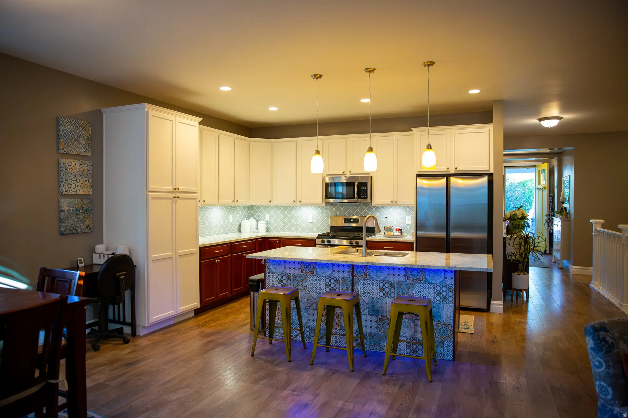 Kitchen featuring wood-finish flooring, two-tone cabinetry, stainless steel appliances, and a tiled backsplash