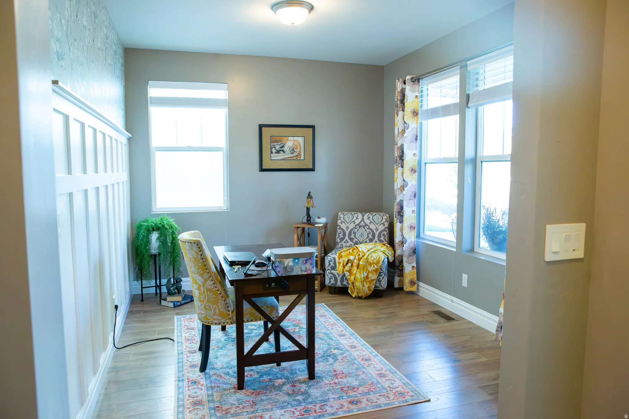 Wood-finish flooring, white board and batten accent wall, recessed lighting, and multiple windows