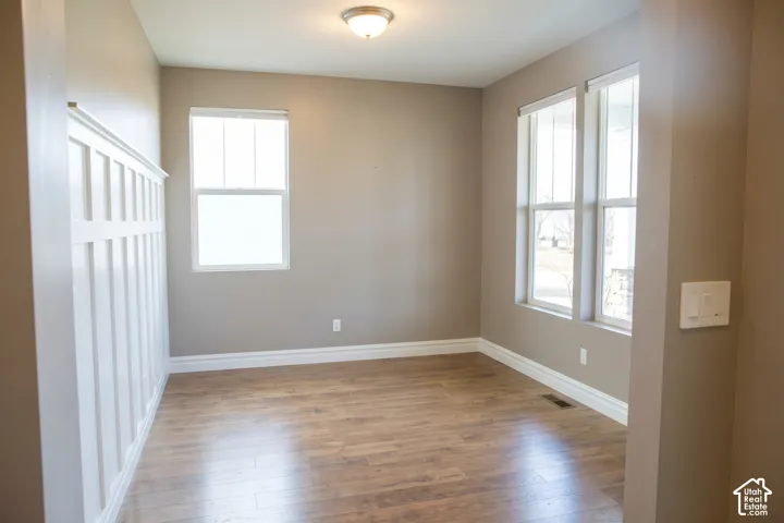Wood-finish flooring, two large windows, one smaller window, overhead flush-mount lighting, and white board and batten wall paneling