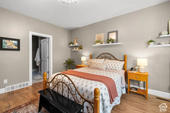 Wood-finish flooring with white baseboards, light neutral wall paint, built-in shelving, and a permanent overhead light fixture
