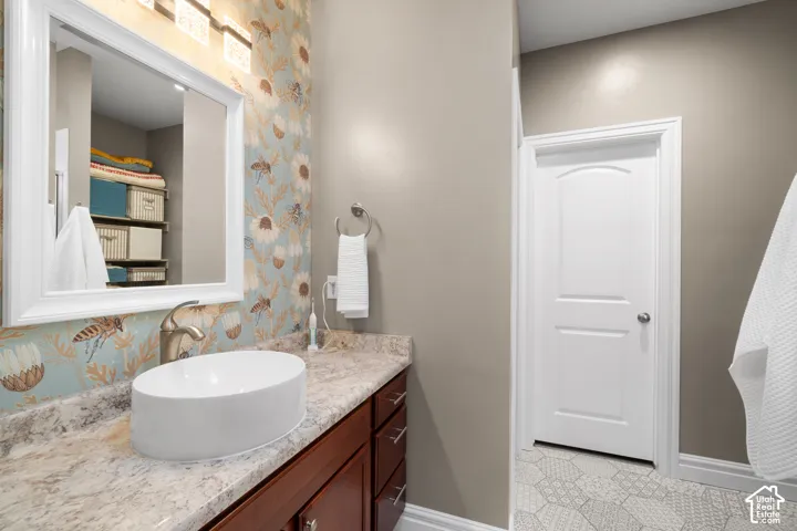 Integrated vanity with a white vessel sink, brushed nickel faucet, and a patterned countertop
