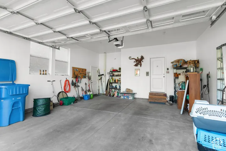 Attached garage with concrete flooring, two high-set windows, and a built-in overhead garage door