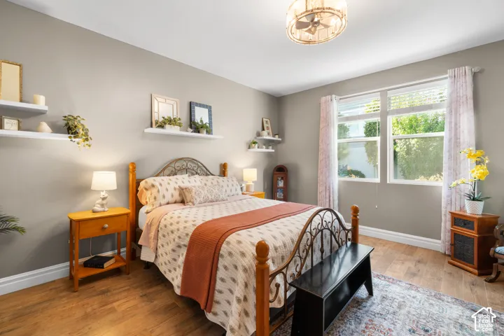 Wood-finish flooring, overhead ceiling fan with integrated lighting, wall-mounted shelving, and window with blinds