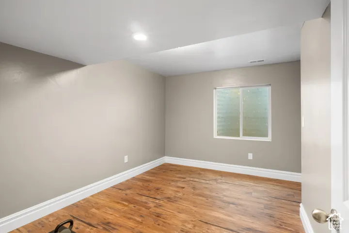 Recessed ceiling lighting, wood-finish flooring, white trim, and a frosted window