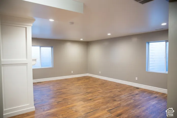 Spacious room featuring wood-finish flooring, recessed lighting, and two windows