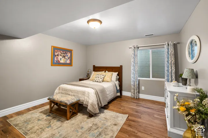Recessed window with decorative curtains, wood-finish flooring, light neutral wall paint, and overhead flush-mount lighting