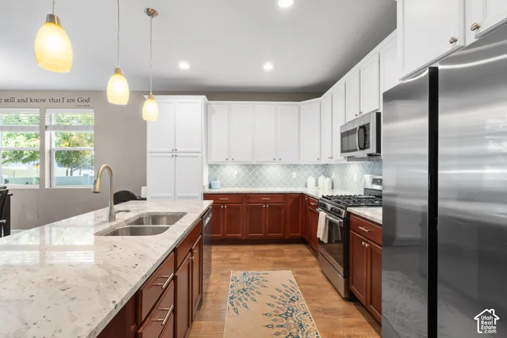 Spacious kitchen featuring an island with a double basin sink, light-colored countertops, and pendant lighting