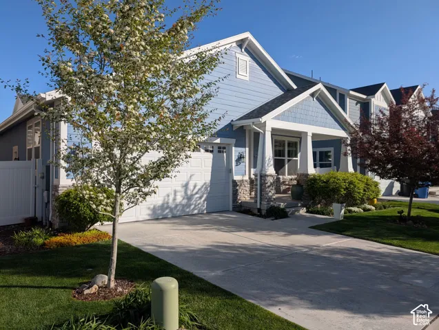 Exterior featuring blue siding, stone accents, gabled rooflines, an attached two-car garage, and a covered front porch