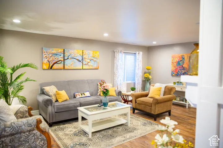 Recessed lighting with a flat ceiling, light gray wall paint, wood-finish flooring, and a white-trimmed window