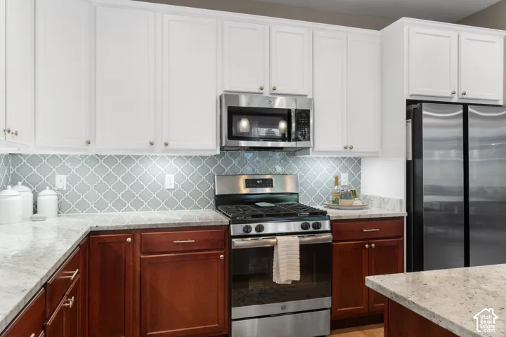 White upper cabinetry with gold-finish hardware, brown lower cabinetry, and light-colored countertops