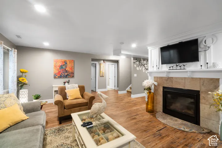 Spacious living area featuring wood-finish flooring, recessed lighting, and a tiled fireplace with a mantel