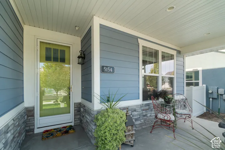 Covered front porch featuring blue horizontal siding, stone veneer accents, and white trim