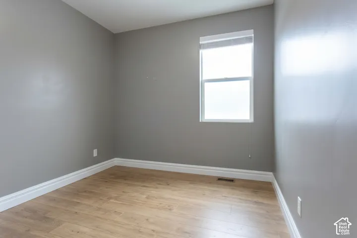 Wood-finish flooring, neutral gray wall tones, white trim, and a window with blinds