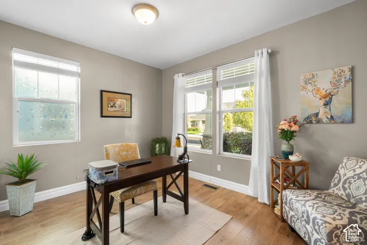 Wood-finish flooring, multiple windows providing natural illumination, neutral wall color, and a flush mount ceiling light fixture