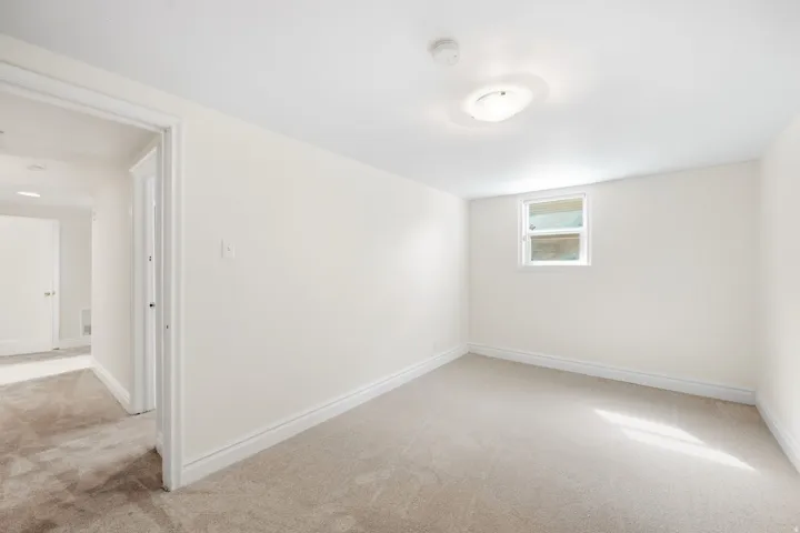 Carpeted room featuring a window and ceiling-mounted light fixture