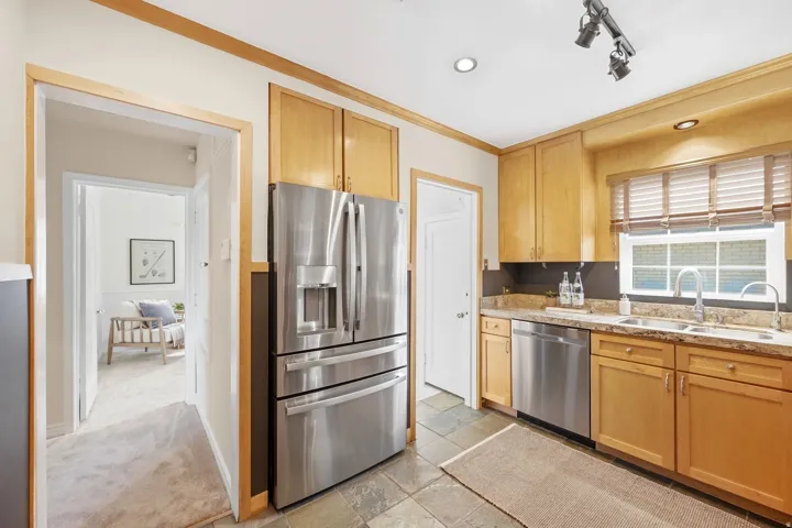 Kitchen featuring stainless steel appliances, wood-finish cabinetry, stone flooring, and recessed lighting