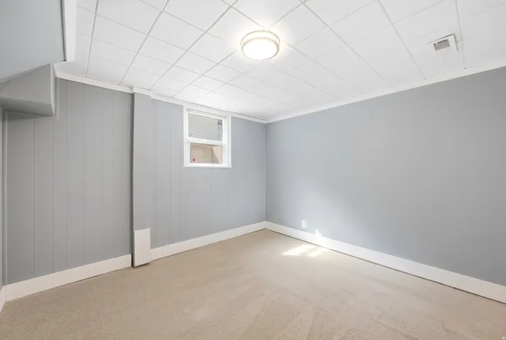 Recessed window, drop ceiling, flush mount ceiling fixture, wall paneling, light-colored carpeting