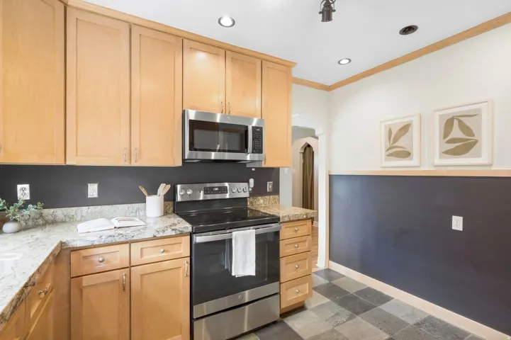 Light wood-finish cabinetry with stainless steel appliances, speckled stone countertops, and recessed lighting