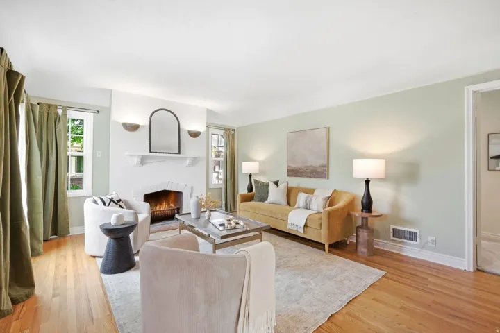 Hardwood flooring, painted walls, fireplace with mantel, window with natural light, and built-in wall sconces