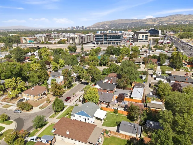 Aerial perspective showcasing a residential area with mature trees and a distant cityscape framed by mountains