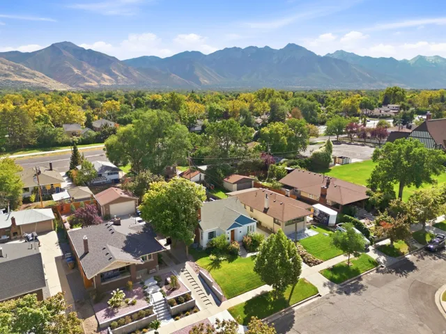 Mountain backdrop, mature trees, residential neighborhood, landscaped front yard, paved street