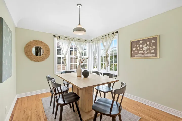 Hardwood flooring, bay windows, and a ceiling-mounted pendant light fixture