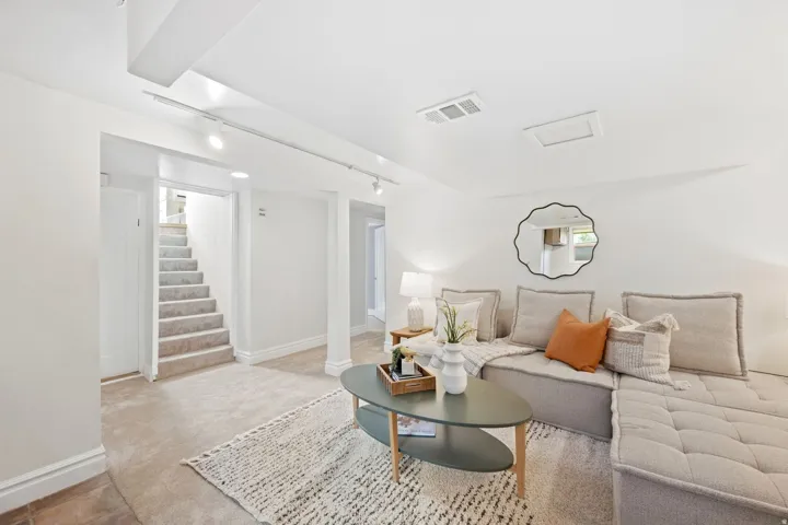 Track lighting illuminates a carpeted living space with white walls