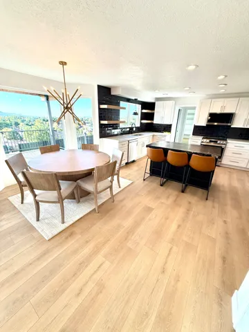Open-concept living space with wood-finish flooring, a contemporary dining chandelier, and large sliding glass doors