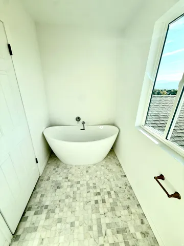 Freestanding soaking tub with wall-mounted fixtures