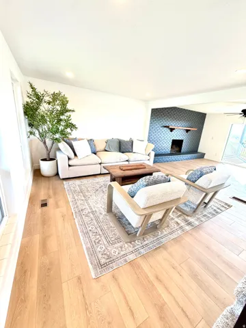 Recessed lighting, wood-finish flooring, and a fireplace with a tiled surround