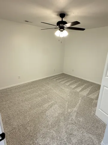 Plush carpeting, neutral wall tones, and a ceiling fan with integrated lighting