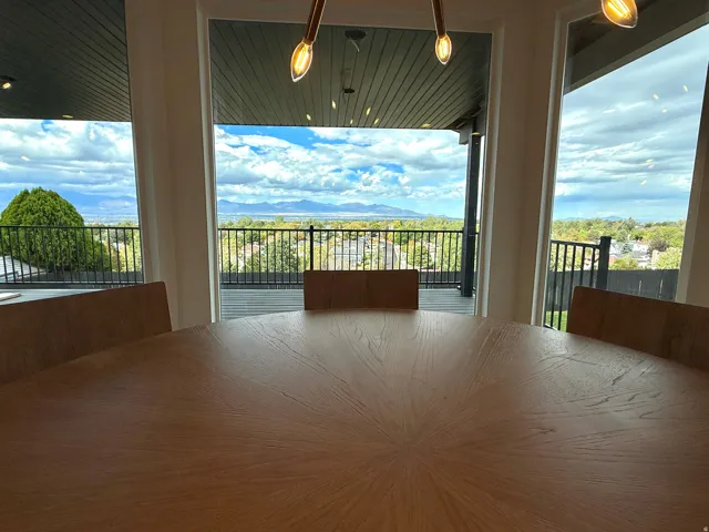 Expansive windows, black metal balcony railing, and a distant mountain range
