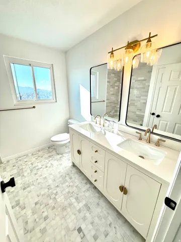 Dual vanity with gold-finish hardware and fixtures, integrated sinks, and a white countertop